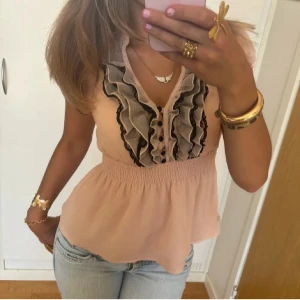 Rosa volangblus - Söt rosa blus med korta ärmar och volangdetaljer i svart och rosa. Köpt på plick men kommer inte till användning.🎀 Storlek M men passar S!!