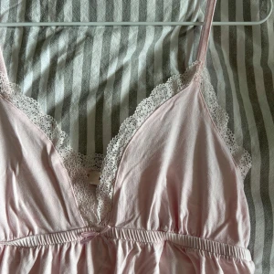 Rosa linne med spetsdetaljer - Säljer ett sött rosa linne som har fina spetsdetaljer samt en rosett🎀 Är i fint skick och knappt använt då det inte passar🫶🏻