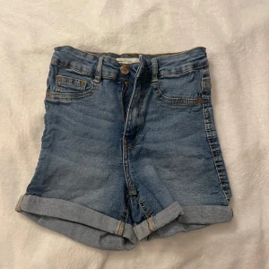 Blå jeansshorts från Gina tricot - Snygga blå jeansshorts från gina tricot i storlek XS. De har en klassisk femficksdesign och är uppvikta vid bensluten för en avslappnad look. I modellen Molly. Perfekta för sommardagar! 