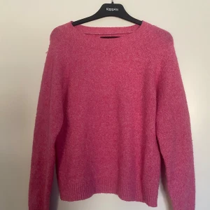 Rosa stickad tröja  - Säljer en mysig rosa stickad tröja från vero Moda . Tröjan har en enkel design med långa ärmar och ribbstickade muddar vid ärmslut och nederkant. Perfekt för kyligare dagar.