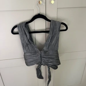 Grå omlott topp - Snygg grå/silvtig topp med knytning i midjan och öppen rygg, skriv för fler bilder💞