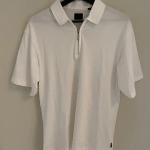 1/4 zip piké från Jack n Jones  - Säljer en stilren vit pikétröja från Jack & Jones med dragkedja framtill. Tröjan har korta ärmar och en klassisk krage, avslappnad look.