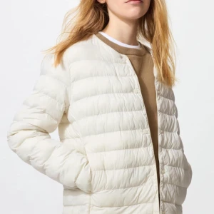 Beige dunjacka från Uniqlo - Säljer en beige Ultra Light Down jacka från Uniqlo. Jackan är quiltad och har en stilren design med knappar framtill. Perfekt för kyliga dagar när du vill hålla dig varm utan att känna dig tung. Lätt och smidig att bära med sig. Inga defekter förutom 2 små fläckar på armen, kontakta privat så kan jag skicka flera. Pris går att diskuteras