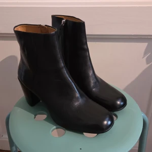 Svarta skinnstövletter från Vagabond - Snygga svarta stövletter från Vagabond i äkta skinn med helskinnsfoder. Modellen har rundad tå, blockklack och dragkedja på insidan. Perfekta till både jeans och kjol för en stilren look.