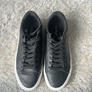 Svarta sneakers från Pull&Bear - Stilrena svarta sneakers från Pull&Bear i storlek 41. svarta snören och vit platt sula.