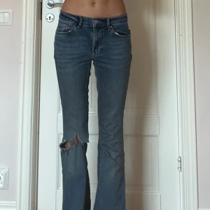 Blå bootcut jeans med slitning - Säljer ett par blå bootcut jeans med snygg slitning vid knät, hålet är gjort själv.❣️Jeansen har klassisk femficksdesign och låg midja. Säljer pga att dom ej kommer till användning. Skriv för fler bilder🙏🏻😊