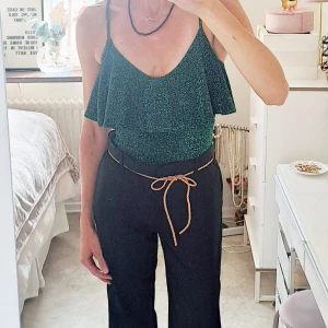 Glittrig grön body med volang - Snygg grön body med glittrigt tyg och tunna axelband från Zara.Toppen har en volangdetalj framtill och är ärmlös, perfekt för att sticka ut lite extra. Passformen är normal och toppen är croppad för en trendig look.