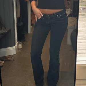 Svarta bootcut jeans - Säljer ett par svarta jeans med bootcut passform och låg midja. Jeansen har klassiska fickor, snygga kontrastsömmar och är tillverkade i ett stretchigt denimtyg.