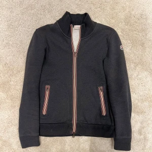 Moncler cardigan  - Moncler cardigan i fint skick ändats en liten skada på ena armen inget man tänker på (se bild) självklart äkta, storlek L men sitter som M.