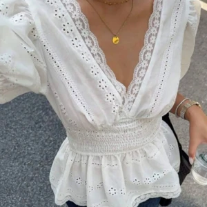Vit blus med spets och puffärm - Superfin vit blus med broderade detaljer och spetskantad v-ringning. Blusen har puffiga korta ärmar, smockad midja och volang nertill. Perfekt för dig som gillar clean stil. Har använt enstaka gång. FINNS I SVART OCKSÅ