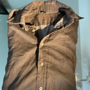 Brun skjorta från Stenströms slimline S - Säljer en brun skjorta från Stenströms i slimline-modell, storlek S. Skjortan har klassisk krage, knäppning framtill med ljusa knappar och är tillverkad i ett mjukt tyg som känns skönt mot huden. Perfekt för dig som gillar stilrena och tidlösa plagg.