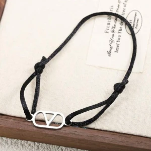 Svart armband med silverdetalj - Stilrent svart armband med justerbar snörning och en cool silverfärgad metallbricka i mitten med V-formad design. Perfekt för dig som gillar minimalistiska accessoarer med en modern touch.