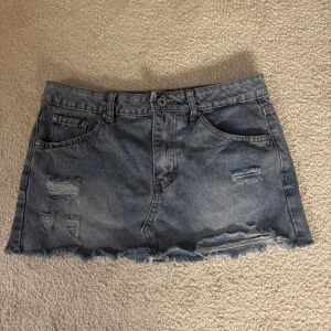 Blå jeanskjol med slitningar - Snygg kort jeanskjol i blå denim med slitna detaljer och fransig nederkant. Passar xs och s. Lowwaisted. Pris kan diskuteras.🩷