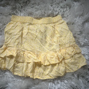 Gul volangkjol från JDY - Superfin gul kortkjol från JDY med småblommigt mönster och volangdetaljer. Kjolen har resår i midjan för en bekväm passform och är gjord i mjuk bomull. Perfekt för soliga dagar när du vill känna dig extra söt! Aldrig använt! Tar frakt!