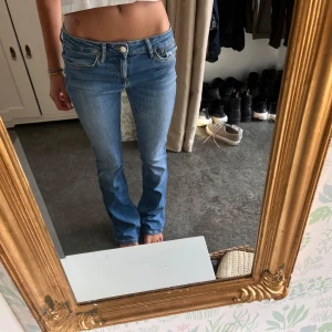 Lågmidjade ljusblå bootcut jeans - Säljer ett par snygga lågmidjade jeans i ljusblå tvätt med klassisk femficksdesign. Jeansen har bootcut-ben och sitter tajt upptill med lite utsvängda ben. Perfekta för dig som gillar en retro vibe och vill ha ett par jeans som sticker ut.