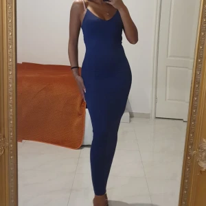 Marinblå långklänning med smala axelband - Säljer en marinblå långklänning med smala axelband och v-ringning. Klänningen är figurnära och har en stilren, minimalistisk look som framhäver siluetten. Perfekt för dig som gillar enkel men snygg stil. Funkar även för strl. S