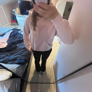 Ljusrosa hoodie med huva - Säljer en supermjuk och basic ljusrosa hoodie med huva och magficka. Perfekt för dig som gillar en enkel och clean stil. Tröjan har långa ärmar och ribbade muddar vid ärmslut och nederkant. Passar perfekt till jeans eller mjukisbyxor.