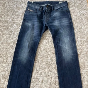Diesel Safado jeans mörkblå W33 L34 - Mörkblå jeans från Diesel, modell Safado. Klassisk femficksdesign med snygga slitningar och raka ben. Jeansen har en slim-straight passform och är tillverkade i slitstarkt denimtyg. Perfekta för dig som gillar en stilren och tidlös look.