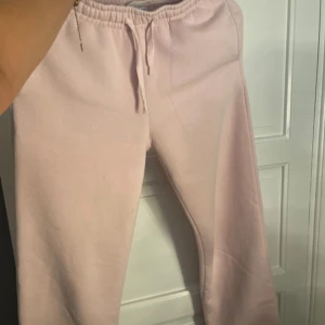 Ljusrosa mjukisbyxor Gina Tricot XS - Supermysiga ljusrosa mjukisbyxor från Gina Tricot, basically basics-kollektionen. De har resår och snörning i midjan för skön passform och är tillverkade i mjuk bomullsmix. Perfekta för chill dagar eller när du vill vara extra bekväm.