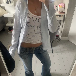 Ljusblå skjorta från H&M - Säljer en stilren ljusblå skjorta från H&M med klassisk krage och knappar framtill. Skjortan har lång ärm och är figursydd för en snygg passform. Perfekt att bära öppen eller knäppt för en clean look.