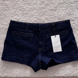 Mörkblå jeansshorts från Zara - mörkblå jeansshorts från Zara med klassisk femficksdesign och synliga kontrastsömmar. Shortsen har en rak passform och är tillverkade i ett stadigt jeanstyg som passar perfekt till sommaren. Virala på TikTok. Går inte längre att köpa! Prislapp kvar helt nya och oanvända. 