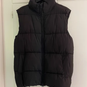 Svart dunväst från Monki - Säljer en svart dunväst från Monki i storlek XS. Perfekt att slänga över en hoodie. Vet ej fraktkostnaden.