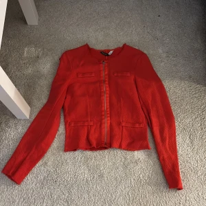 Röd cardigan jacka från Stradivarius - Säljer en snygg röd cardigan jacka från Stradivarius i storlek M. Jackan har en croppad passform, långärmade ärmar och dragkedja framtill. Materialet är stickat och jackan har dekorativa fickor framtill. Perfekt för dig som vill sticka ut lite extra!❤️❤️