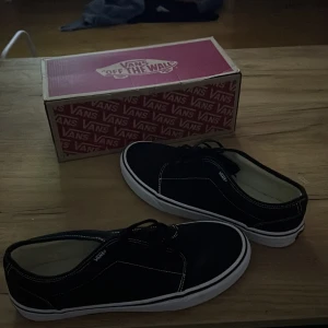 Svarta Vans sneakers med vit sula - Klassiska svarta Vans sneakers med vit sula och kontrasterande vita sömmar. Skorna har snörning och den ikoniska Vans-loggan på sidan samt 'Off The Wall'-märke bak. Ovandelen är i canvas och sulan är platt med det klassiska rutmönstret undertill. Aldrig använda, endast provade.