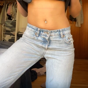 Ljusblå raka jeans låg midja - Säljer ett par ljusblå jeans med låg midja och klassisk rak passform. Jeansen har fem fickor, bälteshällor och stängs med dragkedja och knapp. Perfekta för en avslappnad och trendig look.
