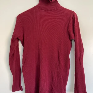 Mörkröd ribbad tröja - Snygg mörkröd tröja med ribbad struktur och lång ärm. Perfekt att styla med jeans eller kjol för en clean look. kragen ger extra värme och den stretchiga passformen gör den bekväm hela dagen.