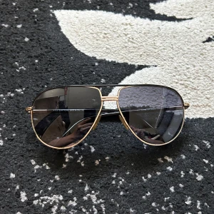 Tom ford solglasögon  - Snygga aviator solglasögon från Tom Ford med guldfärgad metallbåge och mörka tonade glas. Klassisk pilotform som ger en cool vibe. Kommer med originalfodral i brun mocka med Tom Ford-logga.
