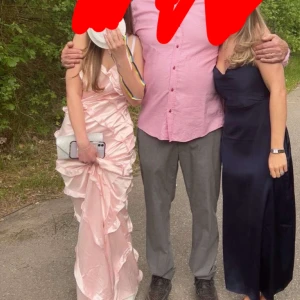 Ljusrosa volangklänning i satin - Säljer en lång, ljusrosa klänning i glansigt satinmaterial med volangdetaljer och omlottkänsla. Klänningen har smala axelband och en elegant, figurnära passform som ger en romantisk vibe. Perfekt för bal eller student! Pris kan diskuteras !
