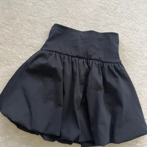 Svart voluminös kjol från Zara - Supersnygg svart kortkjol från Zara med hög midja och voluminös, puffig form. Kjolen är i bomull och har en enkel, stilren look som är lätt att matcha med olika toppar. Perfekt för dig som gillar en trendig och cool vibe.