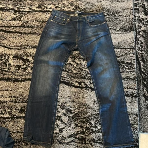 Blå jeans Grant 405 straight fit - Säljer ett par klassiska blå jeans från Grant, modell 405. Jeansen har raka ben, fem fickor och snygga kontrastsömmar. Tillverkade i slitstark denim med en cool tvättad look och patch bak i midjan. Perfekta för dig som gillar en tidlös stil.