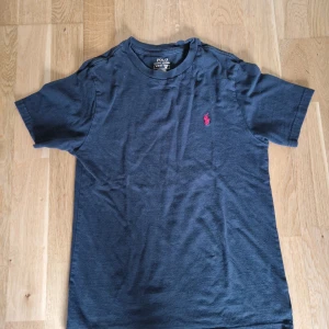 Mörkblå t-shirt från Polo Ralph Lauren - Snygg mörkblå t-shirt från Polo Ralph Lauren med klassisk röd broderad logga på bröstet. T-shirten har rund halsringning och korta ärmar. Tillverkad i mjuk bomull som är skön att bära hela dagen.