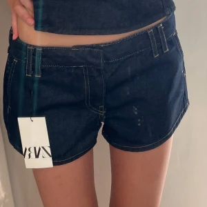 Mörkblå jeansshorts från Zara - Snygga mörkblå jeansshorts från Zara med klassiska gula sömmar och breda hällor för bälte. Modellen är lågmidjad. Perfekta för sommaren och enkla att matcha med olika toppar💕☀️