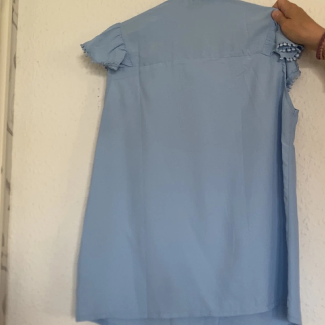 Ljusblå ärmlös blus med volang - 1