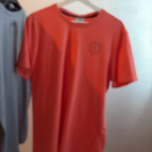 Röd Gymshark t-shirt med tryck - Snygg röd t-shirt från Gymshark med stort svart tryck på ryggen och mindre logga fram. Klassisk rund hals och korta ärmar. Perfekt för dig som gillar att lyfta på gymmet och vill sticka ut med en cool look.