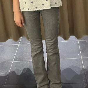 Grå bootcut jeans med mellan midja  - Snygga grå jeans med bootcut-modell och medel midja. Jeansen har klassisk femficksdesign och är tillverkade i mjukt denimtyg. Perfekta för dig som gillar en retroinspirerad look med lite utsvängda ben. Barn Storlek 158 