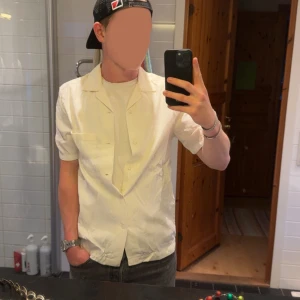 Vit kortärmad skjorta med knappar - Snygg vit skjorta med korta ärmar och klassisk krage. Skjortan har knäppning framtill och en bröstficka, perfekt för en clean och stilren look. Passar dig som gillar enkel och fräsch stil.