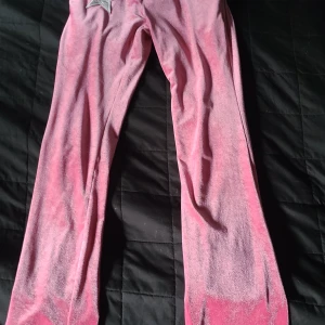 Rosa mjukisbyxor med stjärndetalj - Säljer ett par rosa mjukisbyxor i glansigt velourmaterial med snörning i midjan och en vit silvrig stjärna framtill. Byxorna har en relaxed passform och är perfekta för chill dagar. Supermjuka och bekväma!                              Byxorna är ifrån shein och sparsamt använda. Dem är I stort Xs men sitter som S