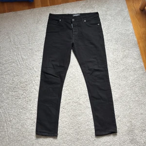 Svarta jeans Dsquared2 - Snygga svarta Dsquared2 jeans med gul patch med logga bak. Jeansen har smal passform och raka ben med en hint av stretch. Skriv gärna för fler bilder osv eller ifall ni har några frågor!