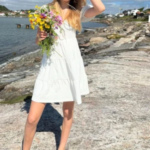 Vit somrig kortklänning med volanger - Jätte gullig o fin vit sommarklänning med korta volangärmar, urringning, söt knytning vid bysten och fler lager vid kjoldelen på klänningen. Den är perfekt för avslutningar eller midsommar samt som vanlig sommarklänning. Klänningen är använd av mig 2 ggr, skolavslutning och midsommar förra året. Kan mötas upp i Stockholm där vi kommer överens 🌸😇