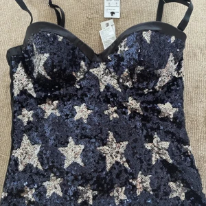 Korsett topp - Glittrig korsettopp från intimissimi med silvriga paljettstjärnor. vadderade kupor och hakknäppning i ryggen. Banden går även att ta av! Super fin till fest✨helt ny