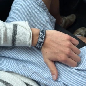 Blått armband från Christian Dior - Snyggt blått armband från Christian Dior med vit text och dekorativa tofsar. Perfekt accessoar för att lyfta din outfit med en exklusiv touch. Justerbar passform och klassisk design.