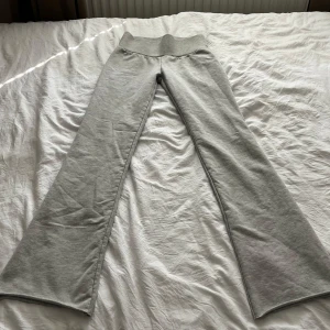 Grå bootcut mjukisbyxor från Nelly - Superbekväma ljusgrå mjukisbyxor från Nelly i storlek XXS. Byxorna har hög midja med bred ribbad mudd och bootcut-ben. Perfekta för chill dagar och har en mjuk bomullskänsla.