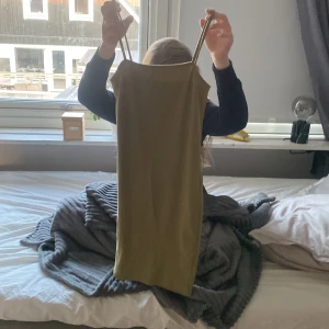 Olivgrön tight klänning med smala band från Newyorker  - Säljer en olivgrön, tight klänning med smala axelband och rak halsringning. Klänningen är kort och har en enkel, stilren design som sitter figurnära.