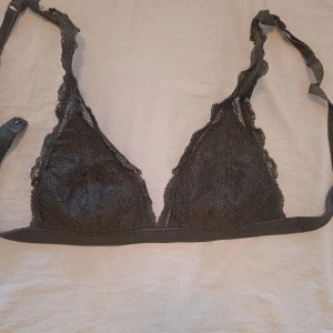 Svart spets bralette - Supersnygg svart bralette med tunna axelband och v-ringad spets framtill. Mjuk och lätt stretchig känsla tack vare polyamid och elastan. Perfekt för lager-på-lager eller som statement-piece under en öppen skjorta.