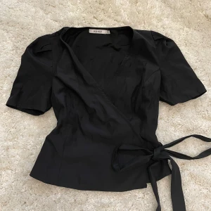 Svart knytblus  - Snygg omlottblus från NA-KD. Väldigt bra skick och knappt använd. Storlek Xs