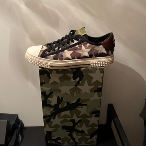 Valentino Sneakers - Snygga sneakers från Valentino med ett unikt stjärnmönster i camouflagefärger. Skorna har en vit sula med nitar och svarta snören. Nypris ligger på runt 7000, mitt pris 949✅. Box ingår
